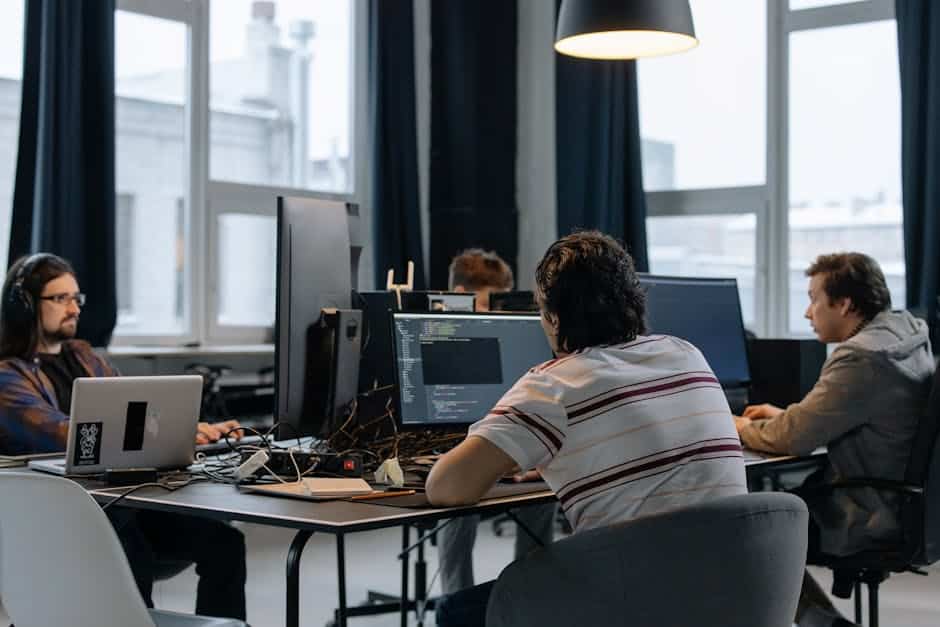 CI/CD pipeline - Team of developers working together on computers in a modern tech office.