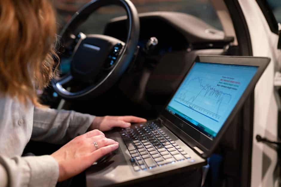 CI/CD pipeline - Female engineer using laptop to analyze vehicle data inside a car for testing purposes.