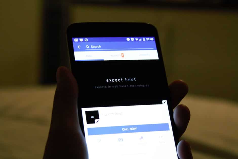 progressive web apps - Close-up of a hand holding a smartphone showing a social media application screen.