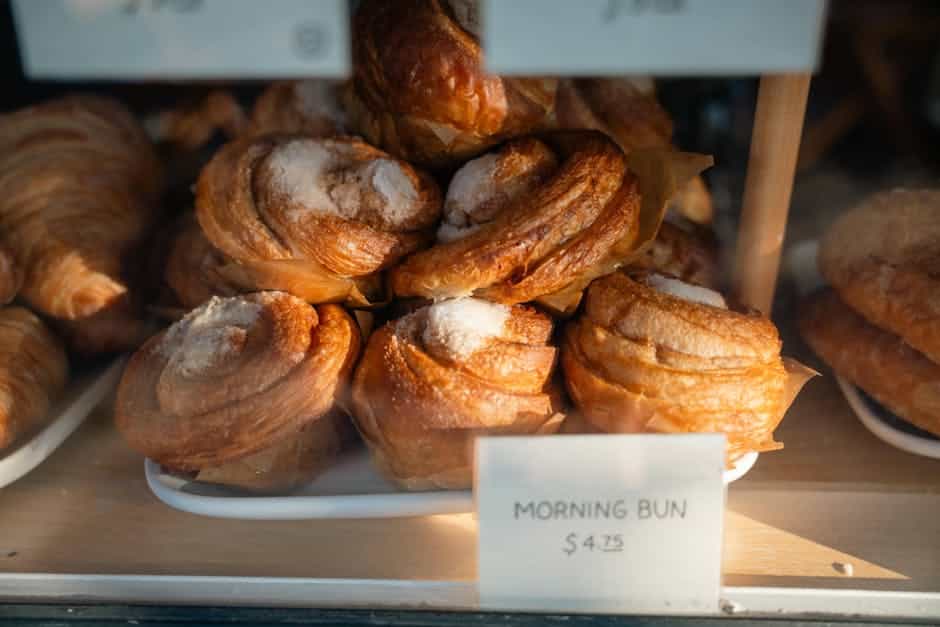 Freshly baked morning buns with sugar coating on display in a bakery window.