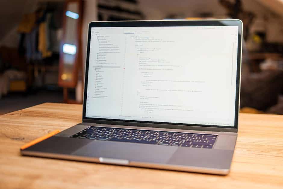weekly web development news - Open laptop with visible code on screen on a wooden desk in a modern, cozy workspace.
